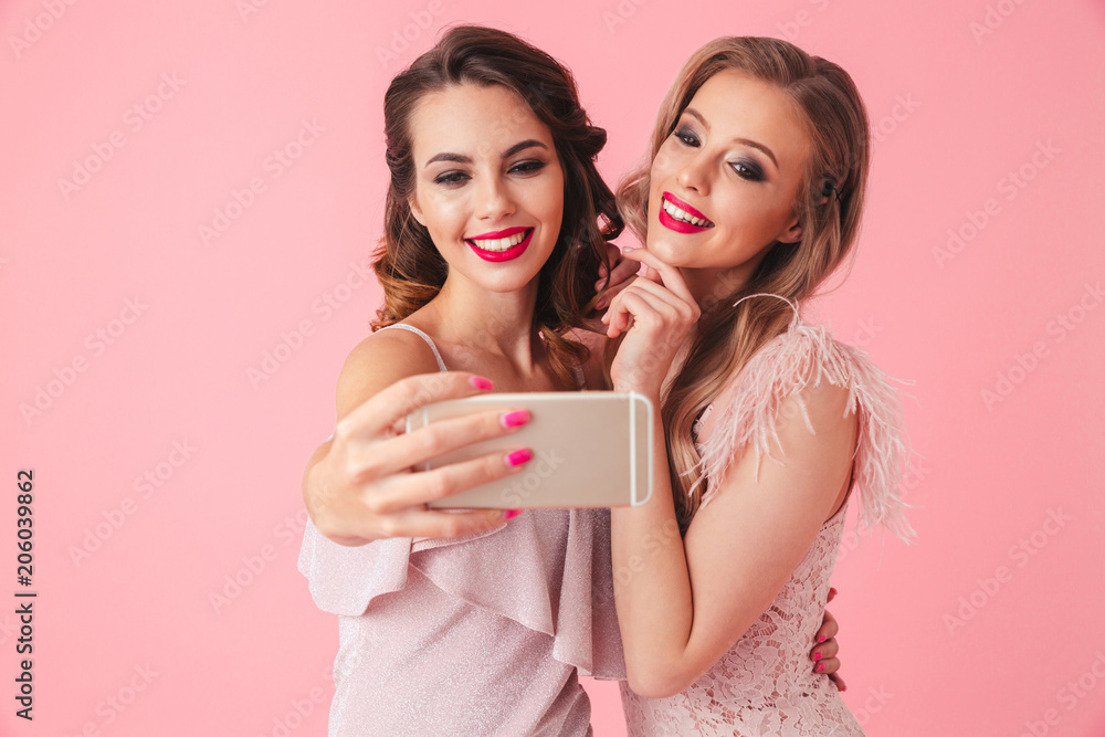Two smiling elegant women in dresses posing together Two smiling elegant women in dresses posing together
