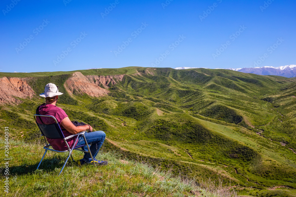 A man sits on a chair and examines the surrounding landscape A man sits on a chair and examines the surrounding landscape