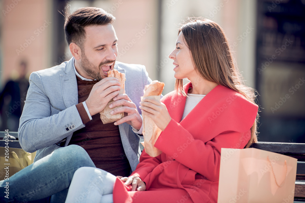 Couple eating sandwiches after shopping Couple eating sandwiches after shopping
