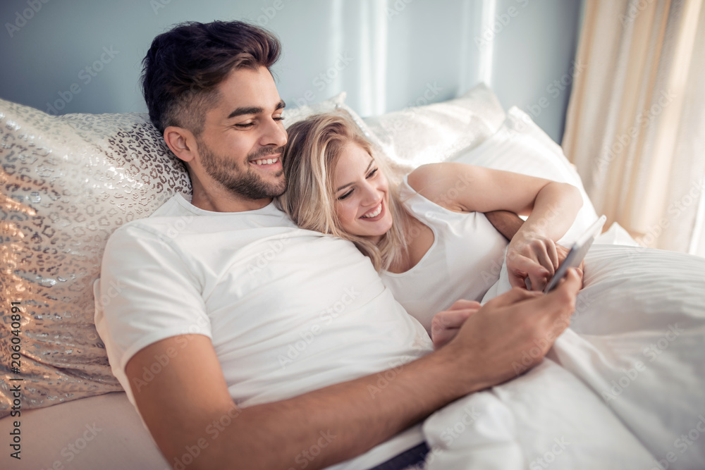 Couple using tablet in their bedroom Couple using tablet in their bedroom
