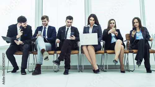 business team looking for information on the Internet using a smartphone and laptop sitting in the lobby of the modern office