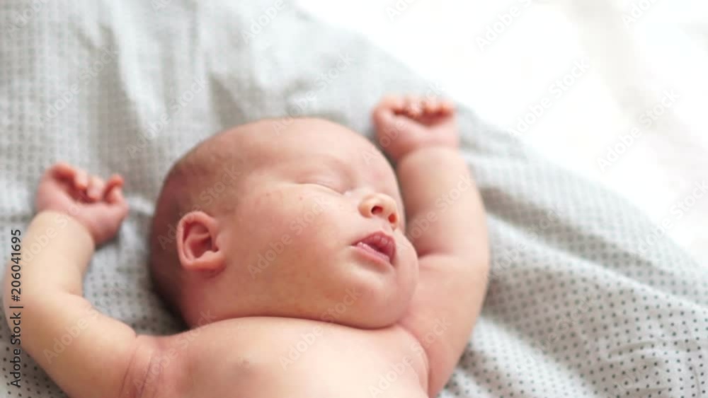 Face of a newborn baby sleeping close up. Portrait of one month baby sleeps on a blanket holding hands up. A serene dream. Newborn baby, child protection Face of a newborn baby sleeping close up. Portrait of one month baby sleeps on a blanket holding hands up. A serene dream. Newborn baby, child protection