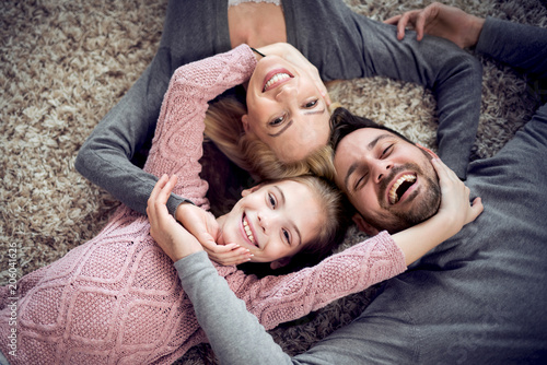 Haapy family are smiling to the camera,lying on the floor photo