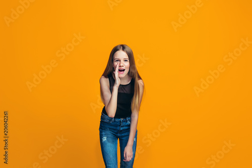 Isolated on yellow young casual teen girl shouting at studio