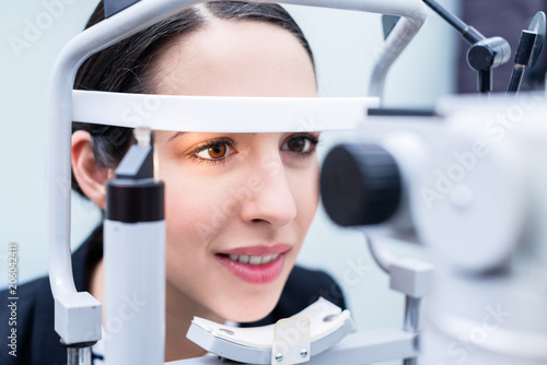 Woman having eyes measured with test device in optician shop