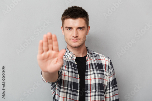 Portrait of a serious young man showing stop gesture