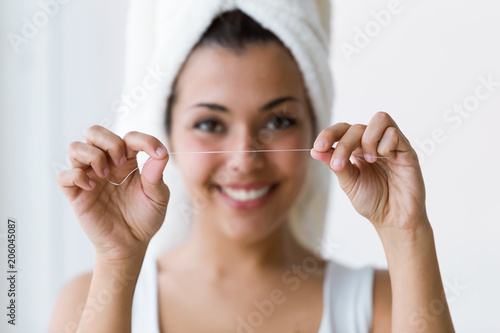 Quadro em tela Pretty young woman using dental floss in a home bathroom.