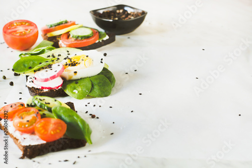 Different sandwiches with vegetables, eggs, avocado, tomato, rye bread on light marble table.Appetizer for party.