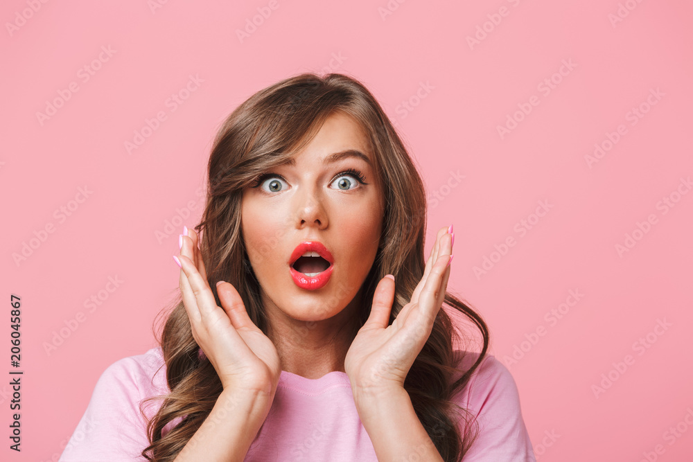Photo closeup of scared woman with long curly hair in basic t-shirt bulging eyes and raising hands in fear or panic, isolated over pink background Photo closeup of scared woman with long curly hair in basic t-shirt bulging eyes and raising hands in fear or panic, isolated over pink background