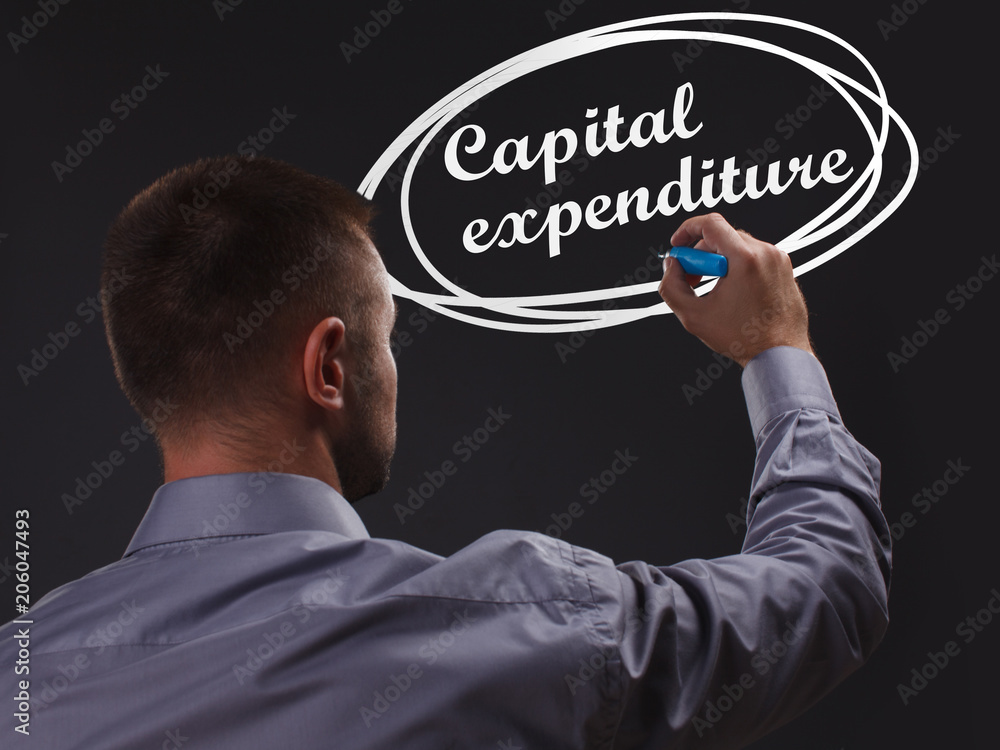 The concept of business, technology, the Internet and the network. Young businessman showing inscription: Capital expenditure