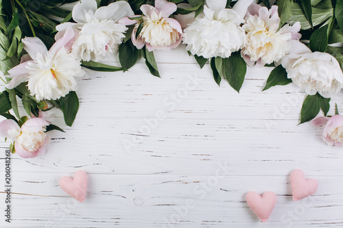 White peonies and pink hearts on a wooden background. Copy space and flat lay.