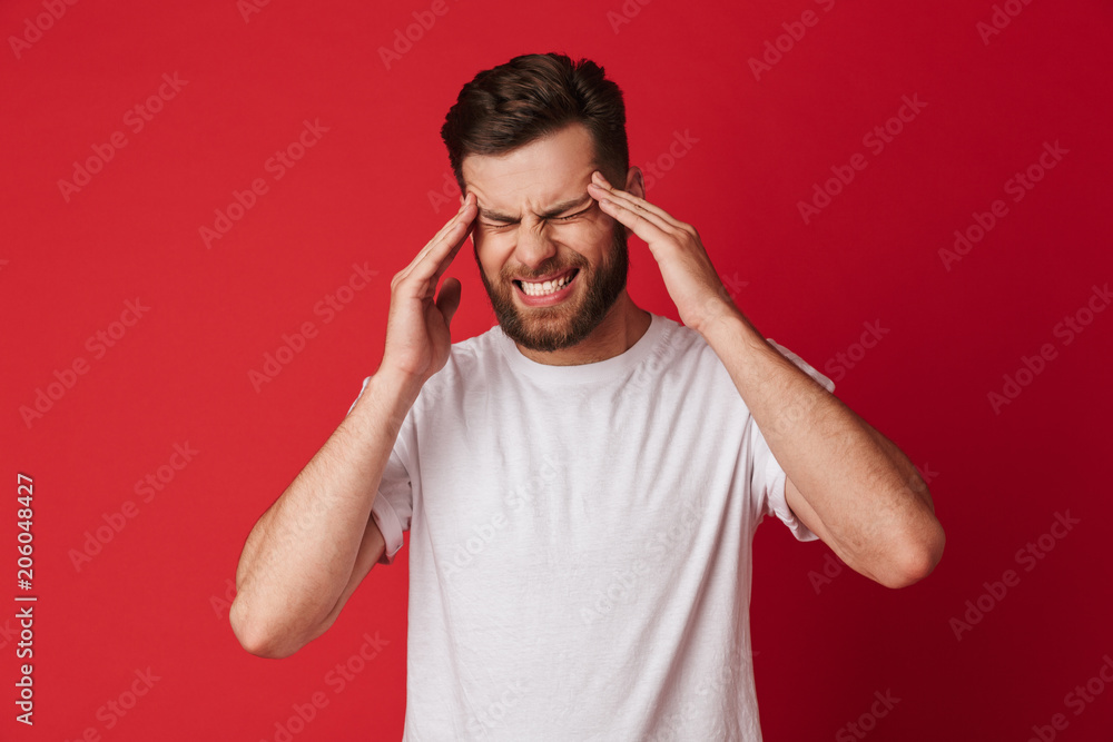 Sad young man with headache standing isolated Sad young man with headache standing isolated