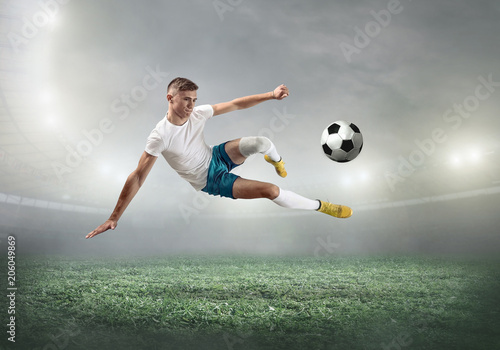 Murais de parede Soccer player on a football field in dynamic action at summer day