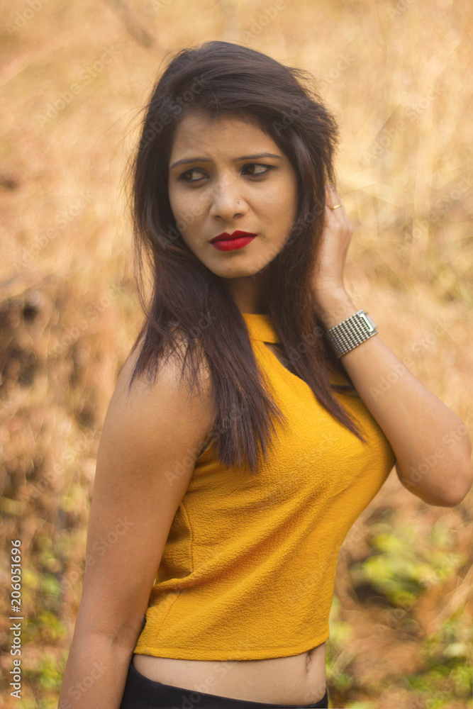 Stylish and beautiful woman with long brown hair wearing yellow blouse looking sideways