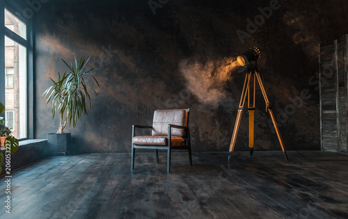 retro spotlight on tripod in grunge wall background with retro brown armchair