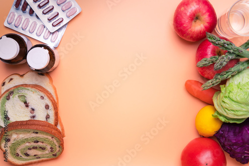 healthy food fruit and vegetable against junk food and supplementary medicine on orange background