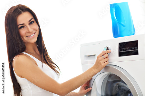 Portrait of young housewife with laundry next to washing machine