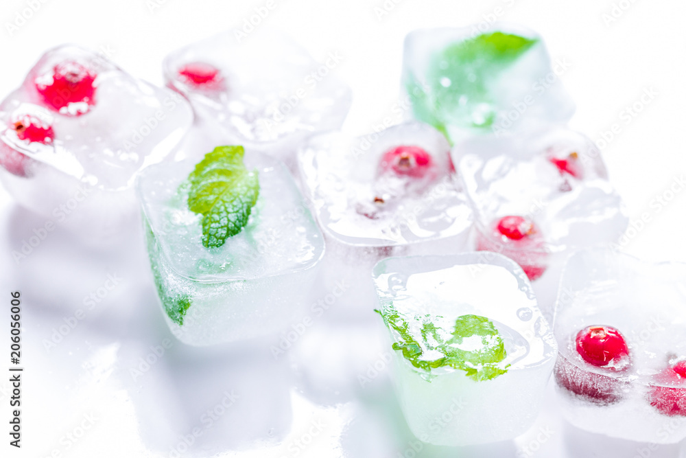 Ice cubes with berries and mint for summer drink on white backgr Ice cubes with berries and mint for summer drink on white backgr