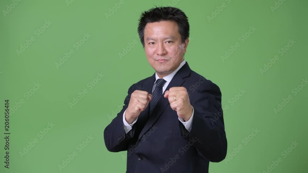 Mature Japanese businessman against green background Mature Japanese businessman against green background