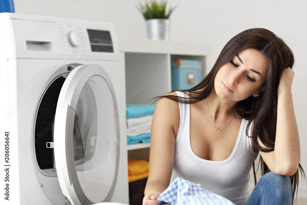 Portrait of young housewife with laundry next to washing machine Portrait of young housewife with laundry next to washing machine
