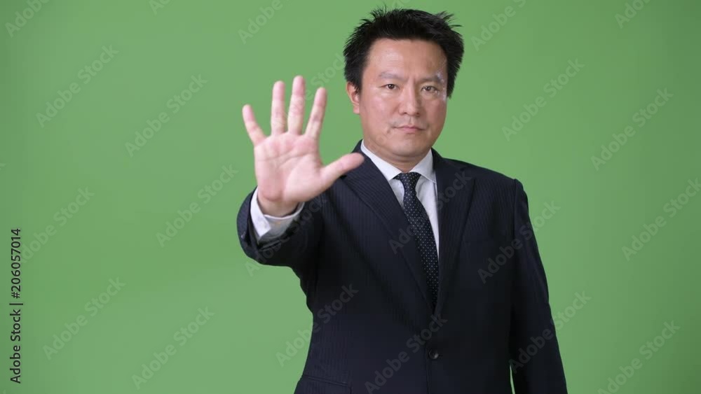 Mature Japanese businessman against green background Mature Japanese businessman against green background