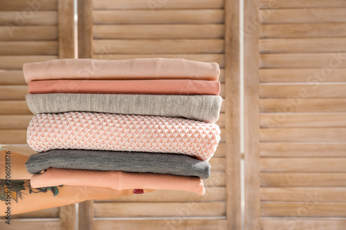 Woman holding stack of clean clothes indoors