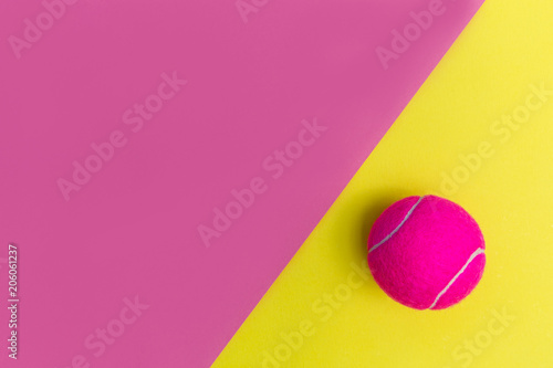 Pink tennis ball on yellow background © Tom Eversley