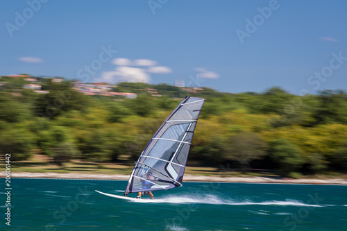 Surfer riding waves in a beautiful sunny day. Young man enjoying the wind and the ocean surfing in Croatia. Sea wave and surfers on the sea. Windsurfing, fun among the waves, extreme sport.