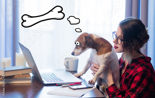 Young businesswoman at home interior with dog near conputer and dreamong about bone photo