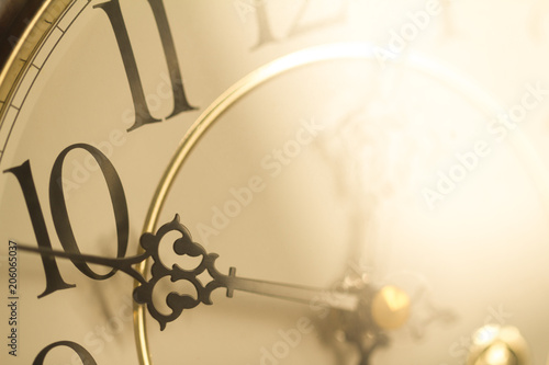 Face of classical grandfather pendulum clock closeup in golden light in concept of golden hour.