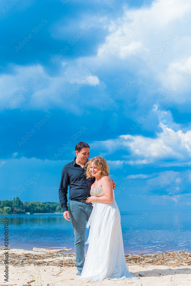 Romantic tenderness bride and groom at sea. Young lady plus size enjoying moments in summer time. Beautiful bride posing with groom in her wedding day, pretty girl in a wedding dress   