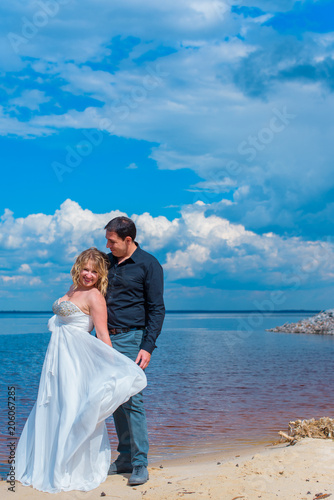 Romantic tenderness bride and groom at sea. Young lady plus size enjoying moments in summer time. Beautiful bride posing with groom in her wedding day, pretty girl in a wedding dress 