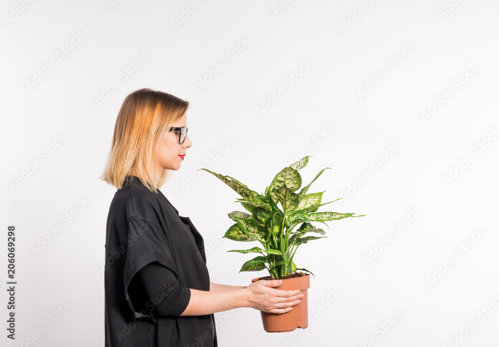 Young beautiful woman with black clothes in studio on white background, holding a plant. Young beautiful woman with black clothes in studio on white background, holding a plant.