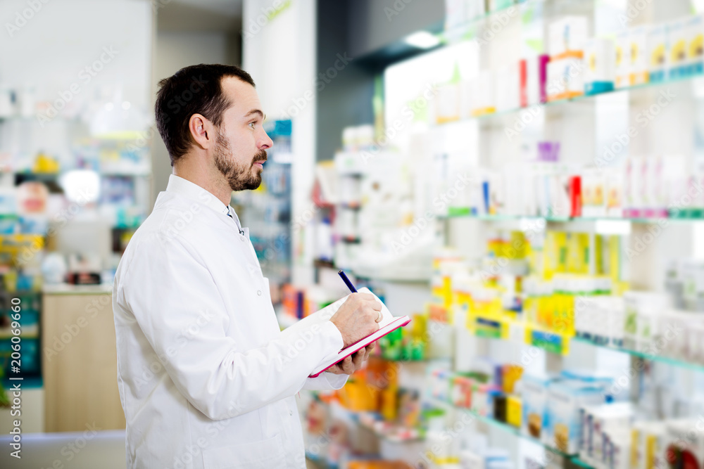 Male pharmacist checking assortment of drugs