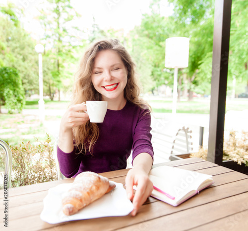 Young woman drinking coffee in city cafe photo