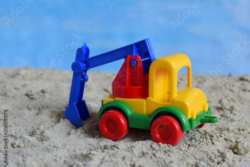Conceptual photo picture of plastic car in desert. Children's toy. Children play in the sand. The concept of a happy childhood. Kids toys excavator