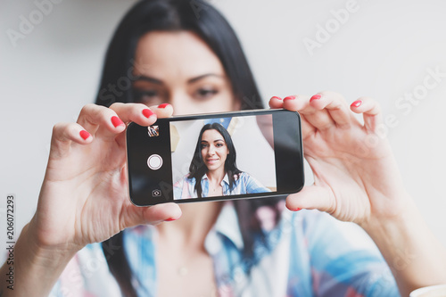 Beautiful woman takes a picture of oneself on the phone