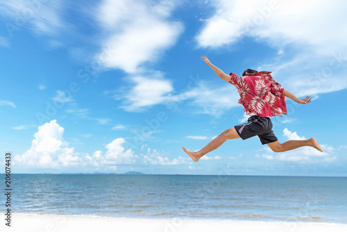 Athletic young man enjoying the summer, jumping in a tropical beach. Summer Concept