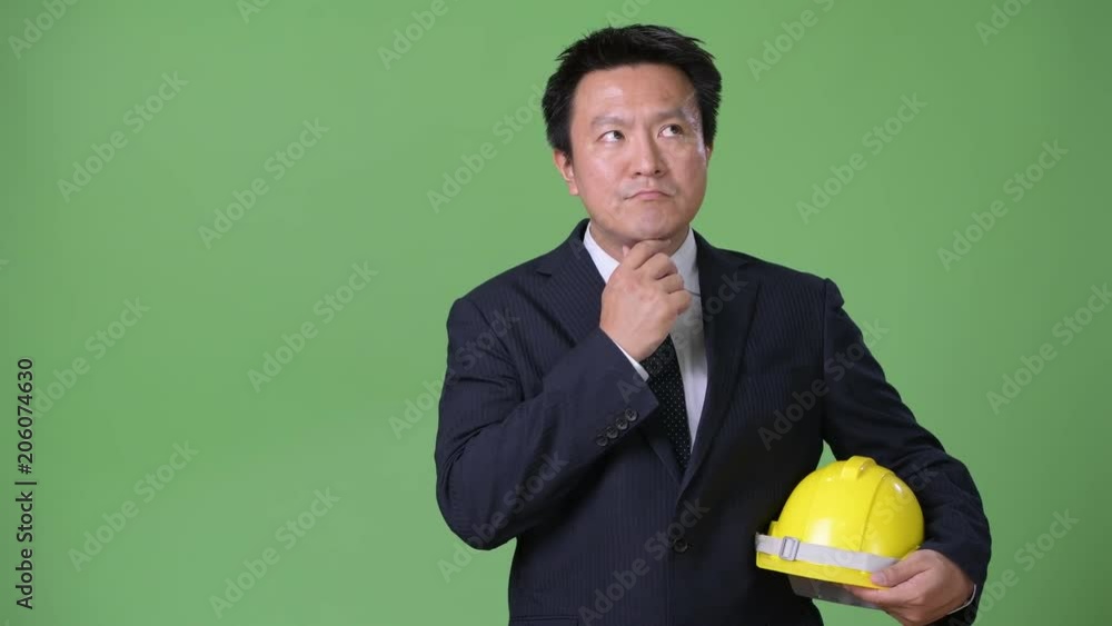 Mature Japanese businessman against green background Mature Japanese businessman against green background