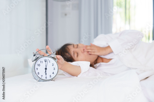 Sleepy young woman stretching hand to trying kill alarm clock in the morning. early wake up.