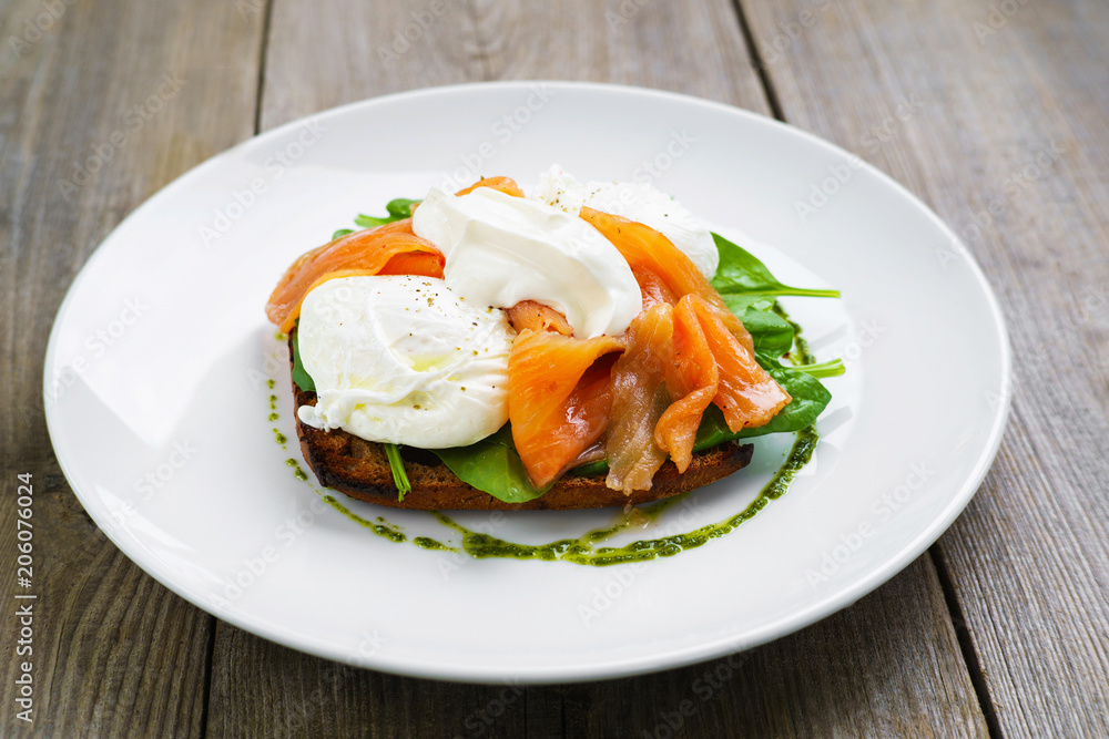 Healthy breakfast, restaurant menu photo, delicious meals with proteins and low fat. Wholemeal bread toast and poached egg with smoked salmon and green salad,