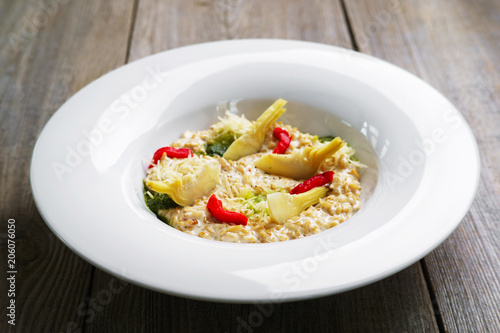 Healthy breakfast, restaurant menu photo, diet food. Chef's creamy oatmeal with artichokes and dried tomatoes, delicious meals with proteins and low fat.