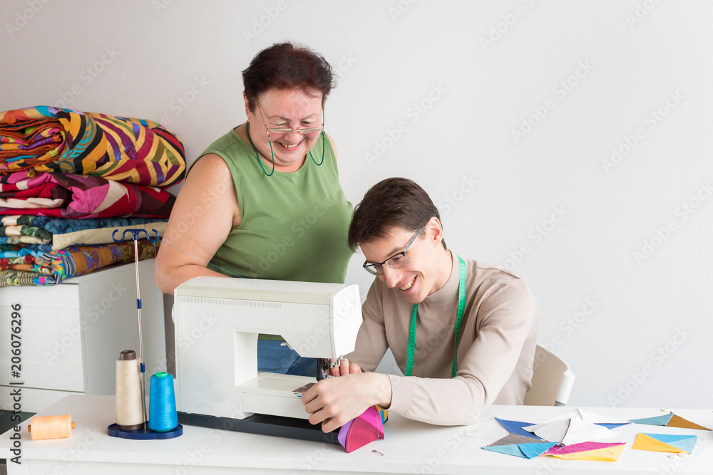 Obraz premium family business, patchwork, occupation concept. there is coworking couple, a young man who is learning to stitching on the sewing machine and an old lady, his grandma, she is an experiences seamstress