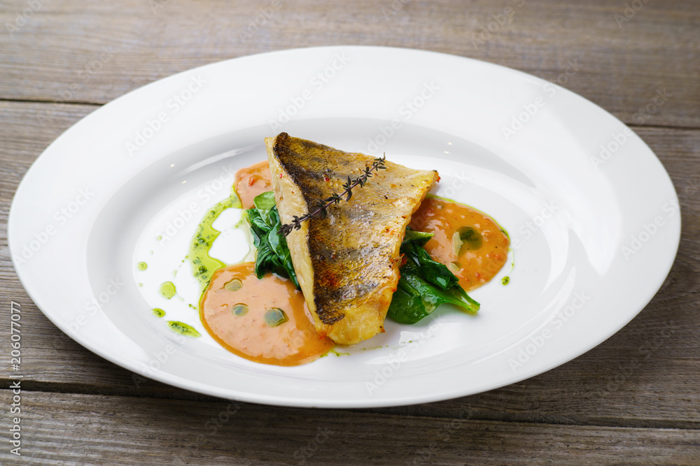 Delicious fish with spinach garnishing and sauce. Mediterranean cuisine, main dish, banquet, food photo, fish restaurant menu concept