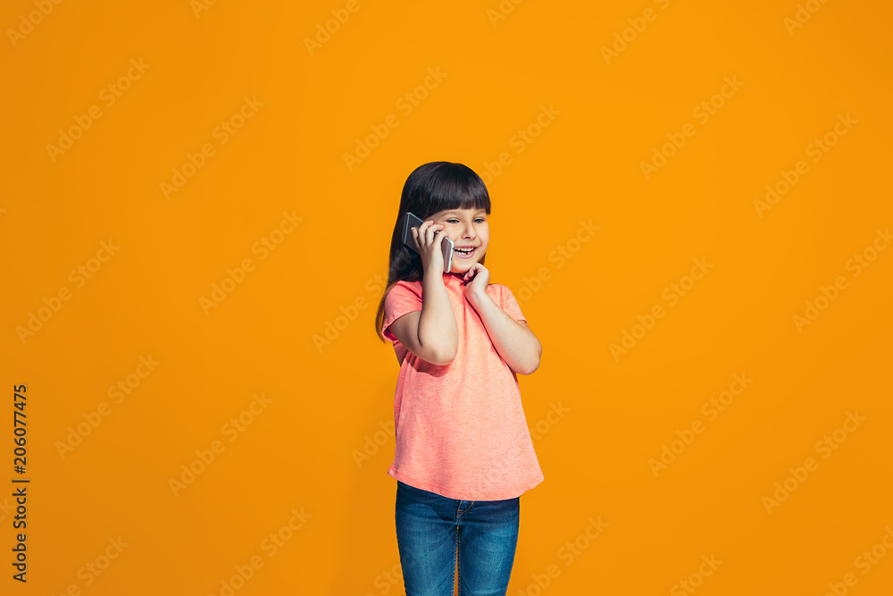 Obraz premium The happy teen girl standing and smiling against orange background.