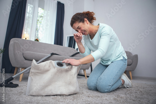 Young lady having forgotten to take her anti allergic pills experiencing annoying fit of dust allergy while dealing with carpet cleaning photo