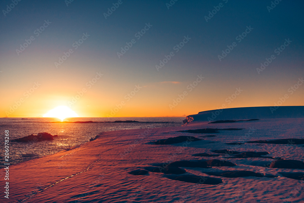Fototapeta premium The polar sunset sunrise that was shot during the extreme expedition to the Vernadsky Research Base. Stunning snow landscape the icy Antarctic surface and Pacific Ocean.