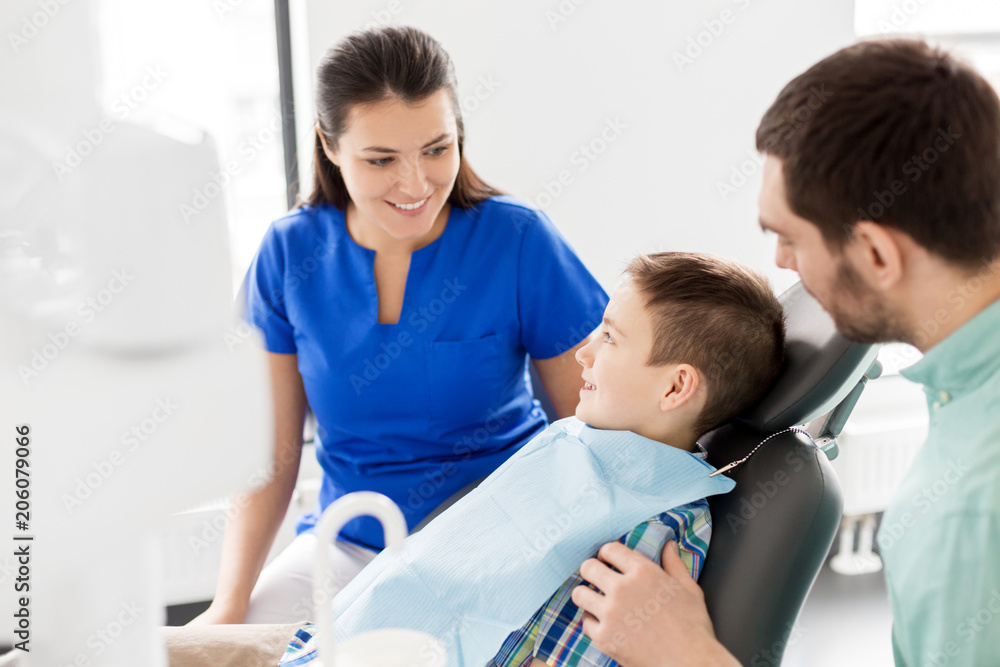 Obraz premium medicine, dentistry and healthcare concept - father and son visiting dentist at dental clinic
