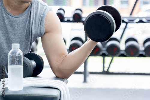 Close-up of a man takes a dumbbell in the gym.