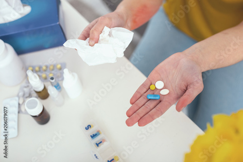 Daily dose. Patient carefully holding prescribed pills over a white table not to drop them